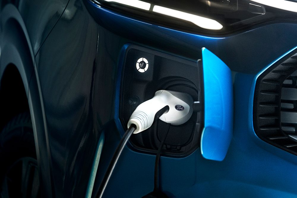 Eine Nahaufnahme eines elektrischen Ladekabels, das in einen Ford E-Transit Custom Elektro-Van eingesteckt ist.