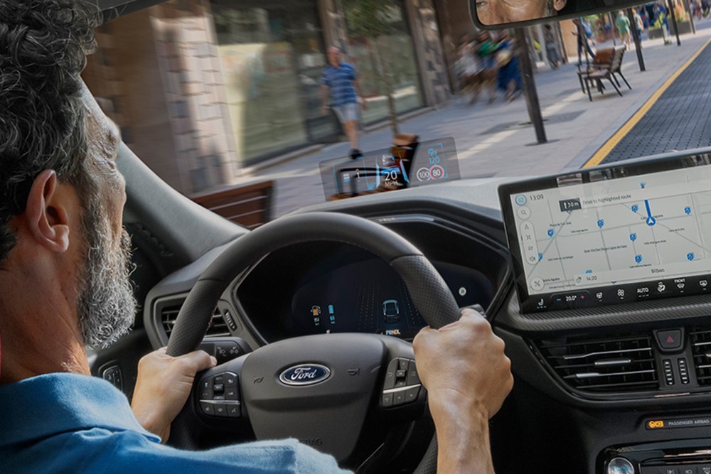 Aufnahme eines Mannes, der einen Ford Kuga auf einer Stadtstraße fährt.