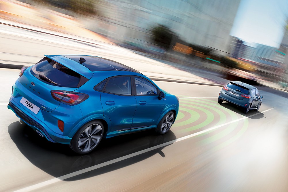 Ford Puma in Blau 3/4-Heckansicht auf einer Straße fahrend mit adaptiver Geschwindigkeitsregelung