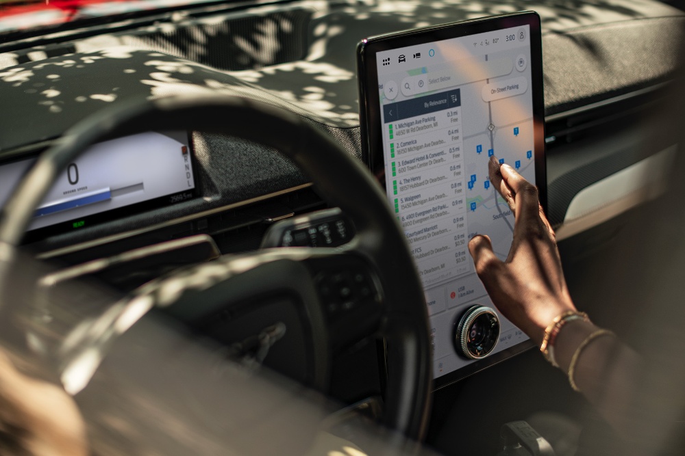 Nahaufnahme einer Frau in einem Ford Mustang Mach-E, die mit dem großen SYNC-Touchscreen interagiert.