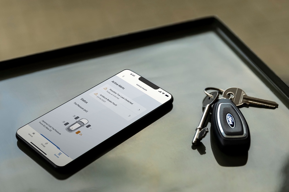 Man läuft hinter einem Ford EcoSport über die Straße und schaut auf sein Smartphone