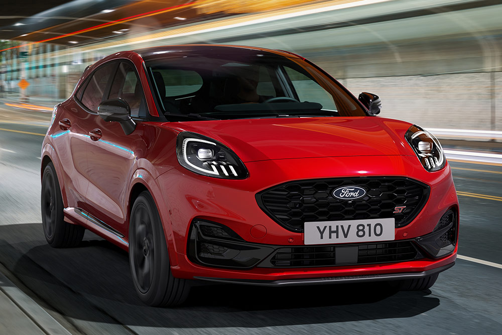 Roter Ford Puma ST fährt auf einer Straße, Front 3/4 Ansicht.