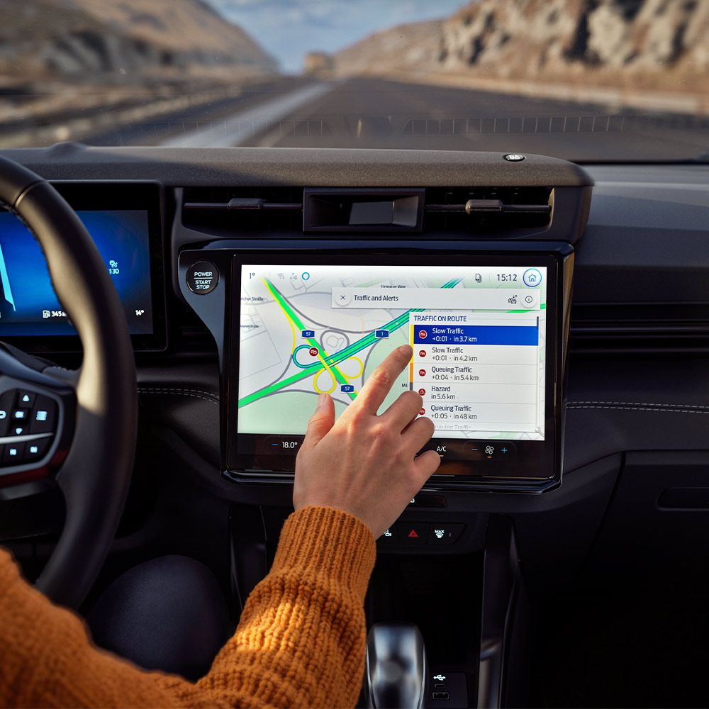 Ein Fahrer nutzt die Vernetzte Navigation- auf dem digitalen Bildschirm eines Ford Puma BlueCruise Edition.