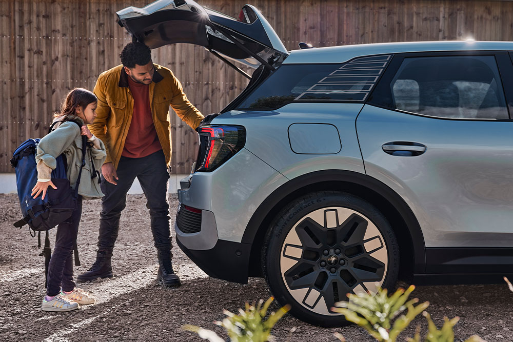 Ford Explorer in Blau. Eine Person und ein Kind beladen den Kofferraum eines blauen Ford Explorer.