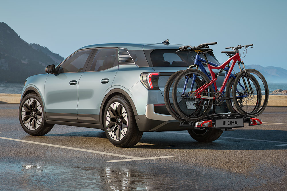 Blauer Ford Explorer fährt durch eine raue Berglandschaft, mit zwei Fahrrädern auf dem Dachgepäckträger.