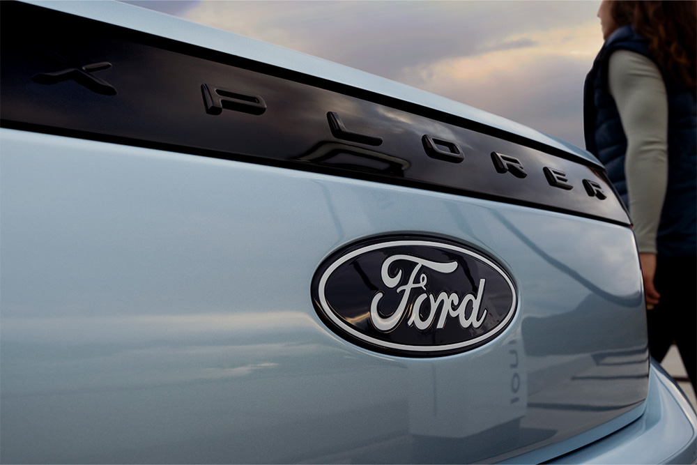 Nahaufnahme des Ford Logos und dem EXPLORER- Schriftzug auf einem hellblauen Ford Explorer