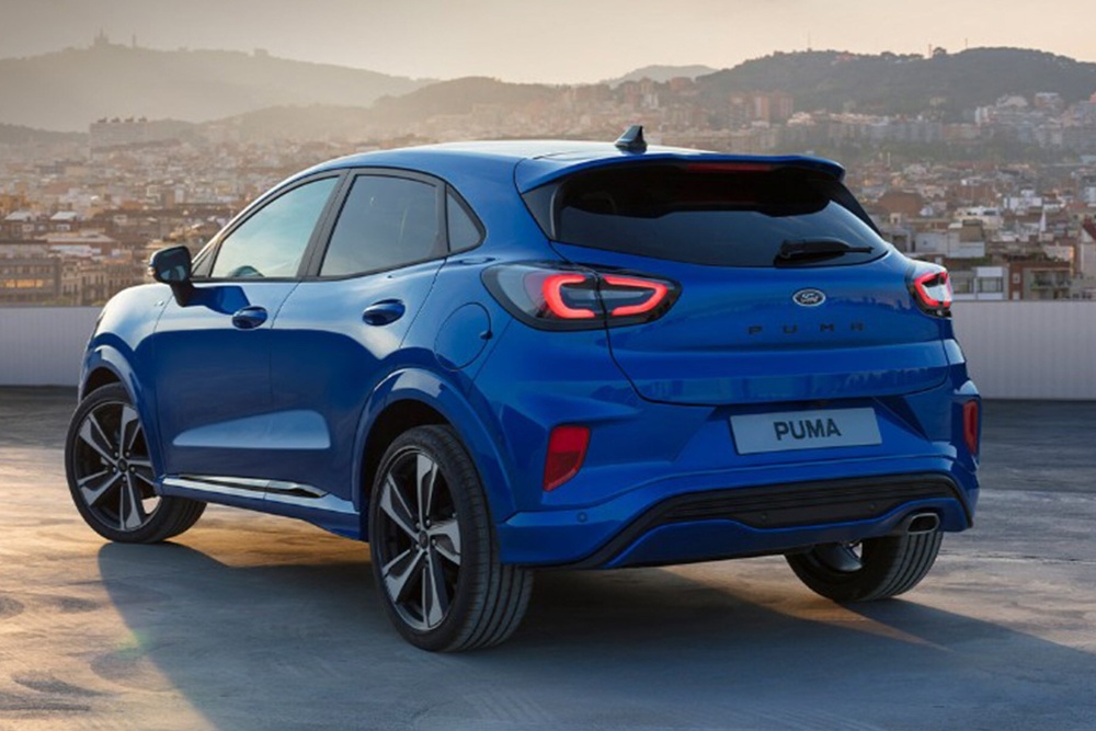 Ford Puma in Blau 3/4-Heckansicht parkend auf Dach vor Stadtpanorama.