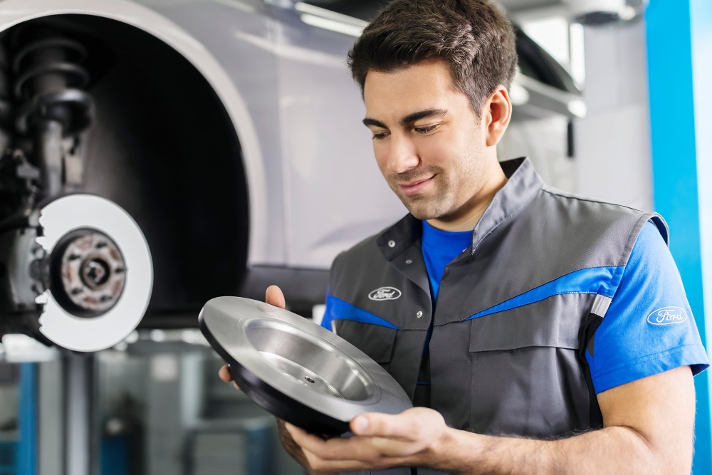Ford Service Werkstatt Mitarbeiter hält Bremsscheiben
