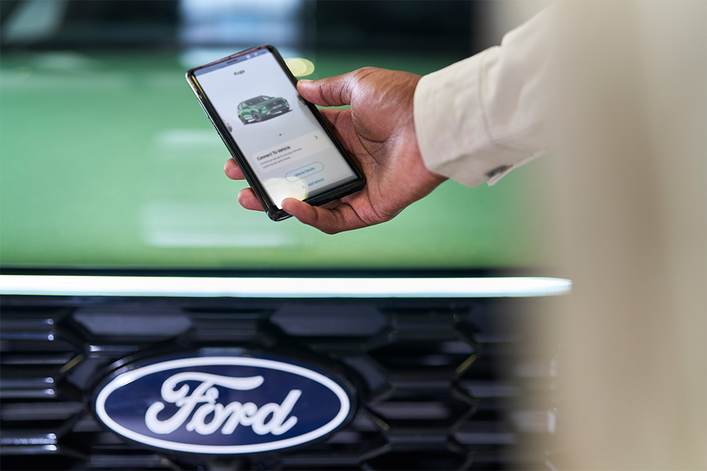 Person schaut auf Smartphone mit angezeigter Ford-App