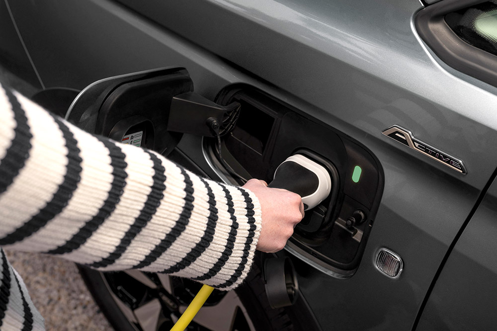 Eine Person schließt ein Ladekabel an einen Ford Transit Connect Plug-in-Hybrid an.