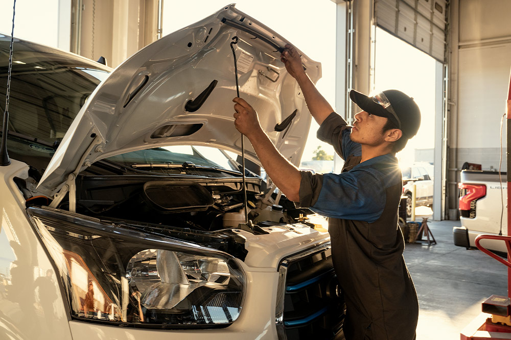 Ford-Mechaniker inspiziert Motorhaube eines Transporters in einer Werkstatt.