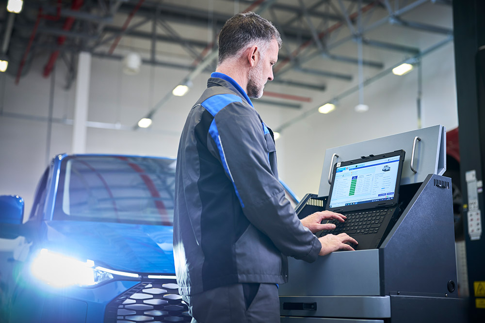 Ein Techniker arbeitet an einem Laptop, der mit einem blauen Ford-SUV verbunden ist.