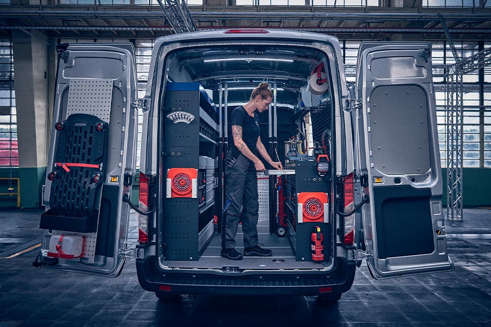 Techniker im hinteren Teil eines Ford-Transporters, der Daten auf seinem Laptop überprüft.