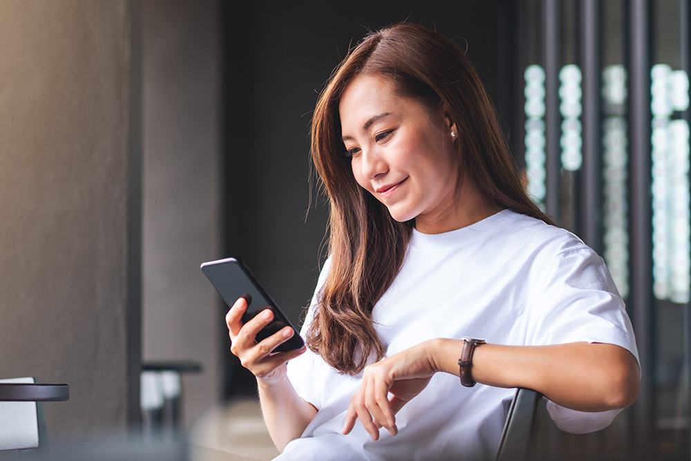 Frau überprüft Echtzeit-Benachrichtigungen von der FordPass App auf ihrem Mobilgerät.