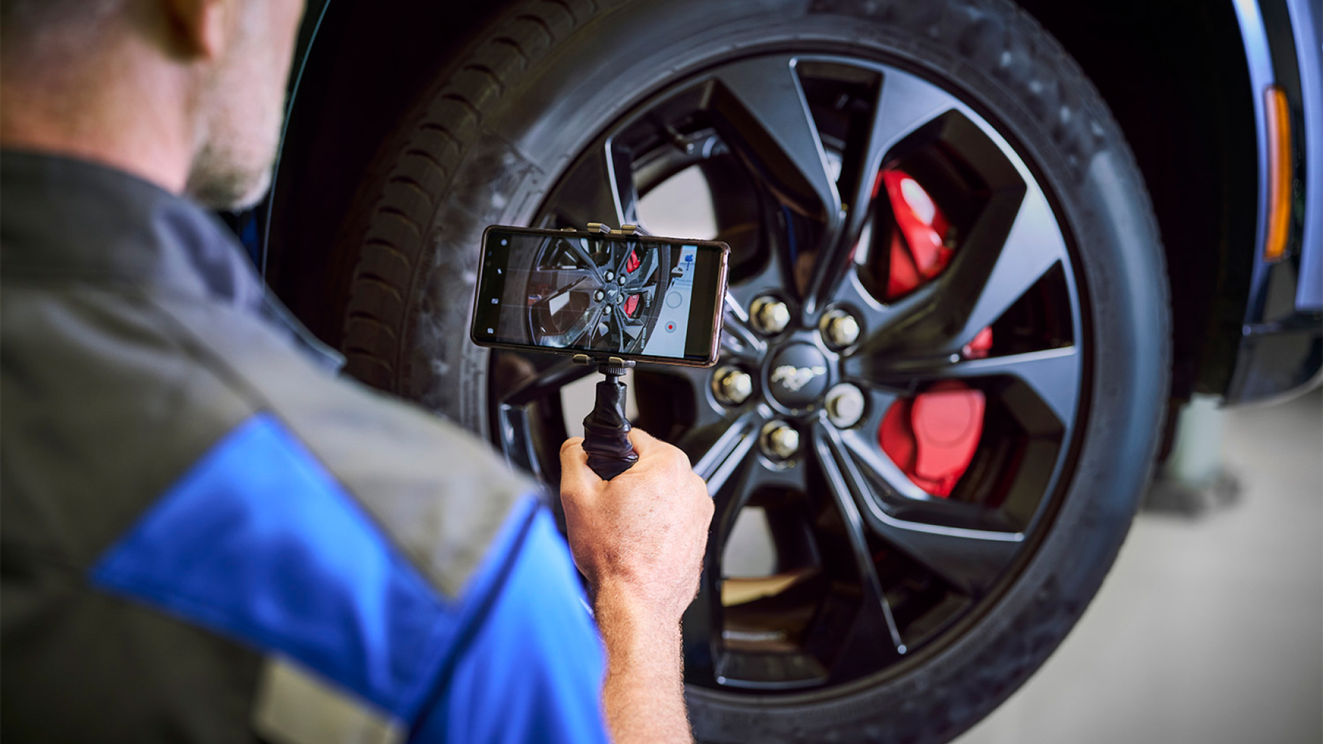 Techniker fotografiert ein Autoreifen- und Bremsenbauteil.